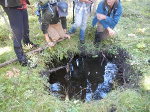 Students and Instructors stand at the edge of a pool dug by bears.  Black and Grizzly bears will frequent these holes during hot days to cool off and to play.   